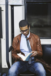 Businessman reading book on the subway train - EBSF000502