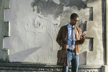 Businessman with smartphone wearing leather jacket and glasses - EBSF000511