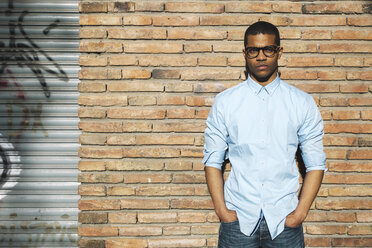 Portrait of serious looking man with hands in his pockets wearing light blue shirt and glasses - EBSF000533