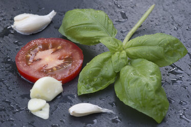 Basilikum, Tomatenscheiben und Knoblauch auf Schiefer - CRF002665