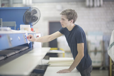 Technician in factory attaching note to machine - SGF001468