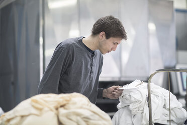 Worker in laundry looking at note - SGF001477