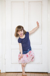 Happy girl dancing at wooden door - LVF003154