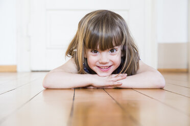 Lächelndes Mädchen auf Holzboden liegend - LVF003161