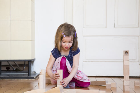 Kleines Mädchen hockt auf dem Boden und spielt mit hölzernen Bauklötzen - LVF003149