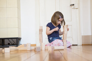 Kleines Mädchen hockt auf dem Boden und spielt mit hölzernen Bauklötzen - LVF003151