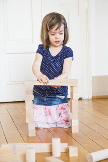 Kleines Mädchen hockt auf dem Boden und spielt mit hölzernen Bauklötzen - LVF003152