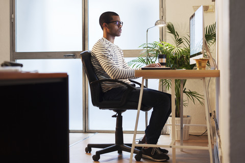 Young creative man working at computer in his home office stock photo