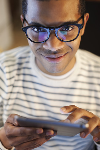 Porträt eines lächelnden jungen Mannes mit Mini-Tablet, lizenzfreies Stockfoto