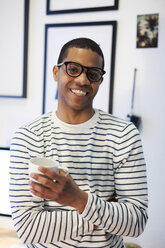 Portrait of smiling young man having a coffee break at his home office - EBSF000555