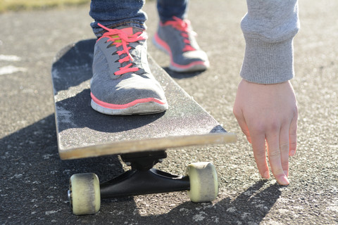 Hand und Turnschuhe einer Frau auf dem Skateboard, lizenzfreies Stockfoto