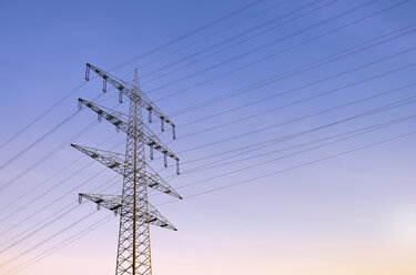 Germany, North Rhine-Westphalia, Dormagen, power pylon in the evening light - GUFF000100