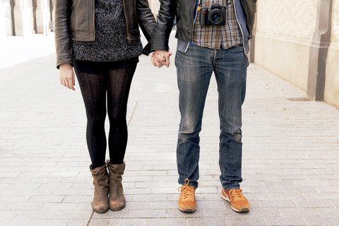 Mann und Frau halten sich auf der Straße an den Händen, lizenzfreies Stockfoto