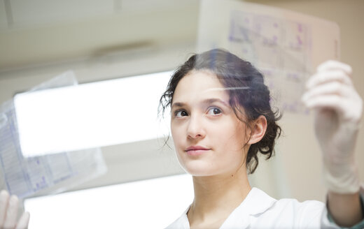 Young lab technician looking at test sheet - DISF001658