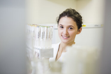 Portrait of smiling lab technician with test tube rack - DISF001601