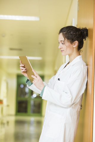 Junger Arzt mit digitalem Tablet auf dem Krankenhausboden, lizenzfreies Stockfoto