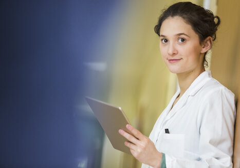 Portrait of smiling young doctor with digital tablet - DISF001661