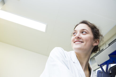 Smiling young lab technician turning round - DISF001623