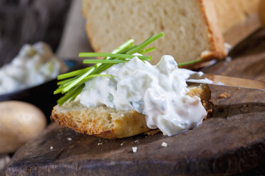 Scheibe Kartoffelbrot, bestrichen mit Kräuterquark und garniert mit Schnittlauch - CSF025268