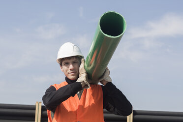 Bauarbeiter trägt Rohr auf der Schulter - SGF001496