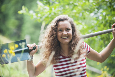 Portrait of smiling young woman with spade in a garden - HHF005288