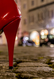 Red high heel on cobblestone street at night - EJWF000755