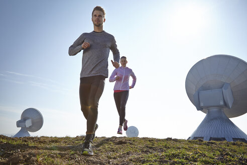 Germany, Raisting, young couple jogging at ground station - KDF000706