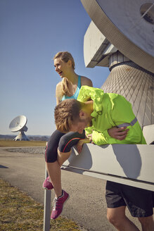 Germany, Raisting, young jogger couple having a rest at ground station - KDF000707