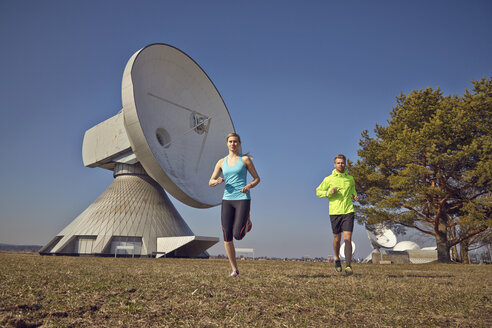 Germany, Raisting, young couple jogging at ground station - KDF000715