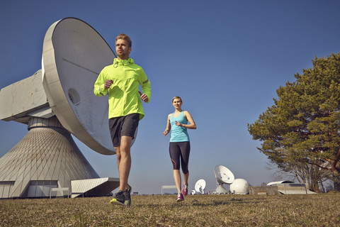 Deutschland, Raisting, junges Paar beim Joggen an der Bodenstation, lizenzfreies Stockfoto