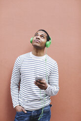Junger Mann hört Musik mit grünen Kopfhörern - EBSF000567