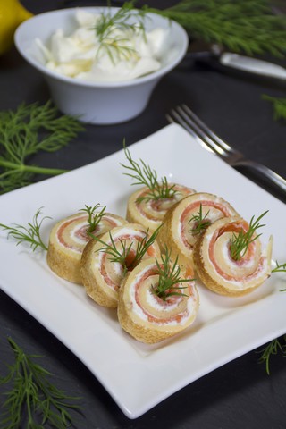 Pfannkuchenröllchen mit Räucherlachs und Frischkäse, garniert mit Dill, lizenzfreies Stockfoto