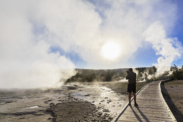 USA, Wyoming, Yellowstone-Nationalpark, Unteres Geysirbecken, Tourist fotografiert den Dampf der Geysire am Morgen - FOF008003