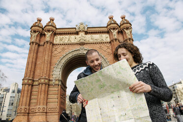 Spain, Barcelona, happy couple watching city map in front of trymphal arch - GEMF000184