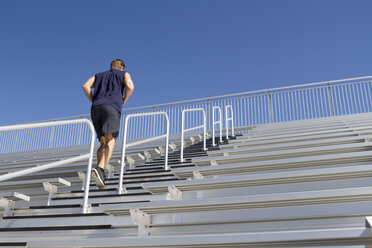 USA, Kalifornien, San Luis Obispo, junger Mann läuft die Treppe einer Tribüne hinauf - JABF000002