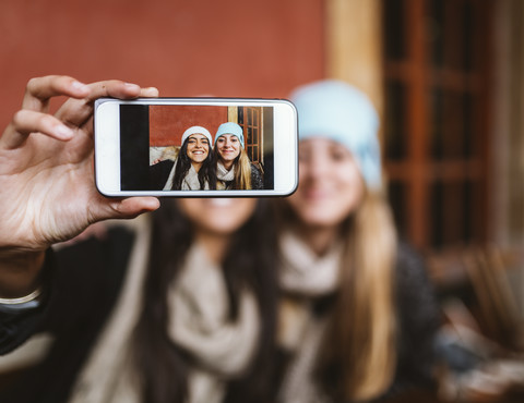 Selfie von zwei Freundinnen auf dem Display eines Smartphones, lizenzfreies Stockfoto
