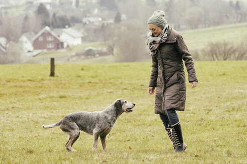 Frau beim Sport mit Hund auf einer Wiese - ONF000805