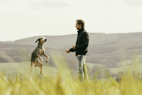 Mann beim Sport mit Hund auf einer Wiese - ONF000812