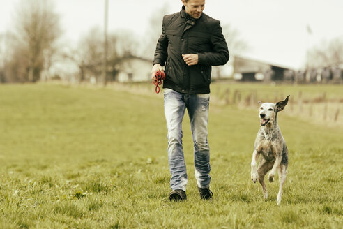 Mann beim Sport mit Hund auf einer Wiese - ONF000816