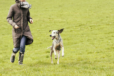 Frau läuft mit Hund auf Wiese - ONF000817