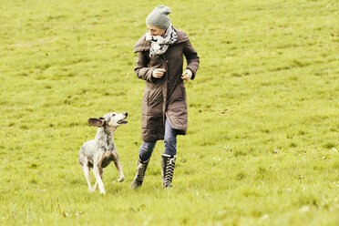 Frau läuft mit Hund auf Wiese - ONF000818