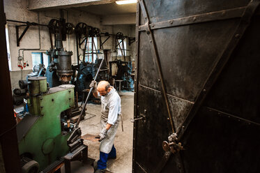 Älterer Schmied bei der Arbeit im Hammerwerk - HHF005324