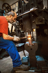 Älterer Schmied bei der Arbeit im Hammerwerk - HHF005326