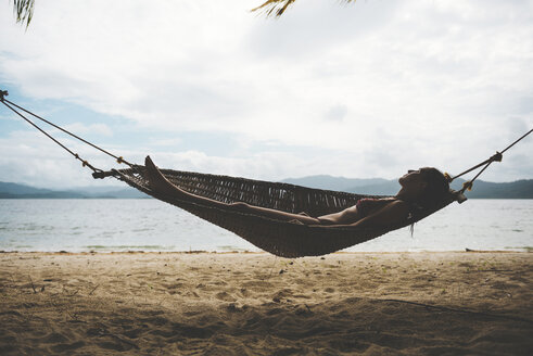 Philppines, Visayas, Woman wearing bikini relaxing on a hammock in the evening - GEMF000190