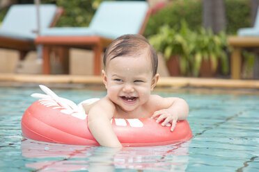 Thailand, happy baby girl with floating tire in swimming pool - DRF001573