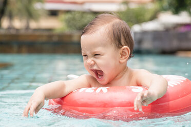 Thailand, schreiendes Babymädchen mit Schwimmreifen im Schwimmbad - DRF001574