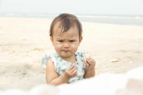 Porträt eines kleinen Mädchens mit Sand im Mund am Strand - DRF001576