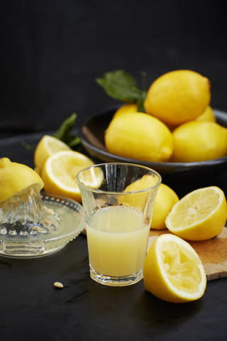 In Scheiben geschnittene Zitronen auf einem Schneidebrett und frisch gepresster Zitronensaft, lizenzfreies Stockfoto