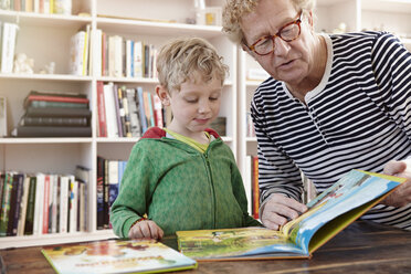 Großvater und Enkel lesen gemeinsam ein Kinderbuch - RHF000753