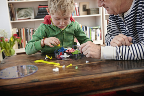 Großvater und Enkel beim Zusammenbau einer Spielzeuguhr, lizenzfreies Stockfoto